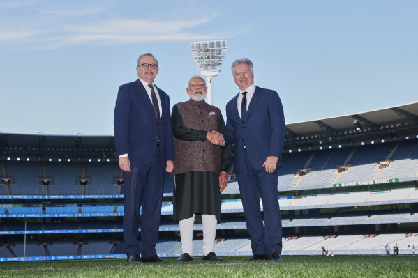 Indian Prime Minister Narendra Modi, center, shakes hands with former Australian cricket captain Steve Waugh, right, as Australian Prime Minister Anthony Albanese watches at the Melbourne Cricket Ground in Melbourne, Australia, Friday, July 10, 2026. (AP Photo/Hamish Blair)